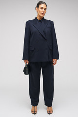 Profile view of model wearing the Oroton Tapered Pinstripe Pant in North Sea and 95% WOOL 5% ELASTANE for Women