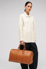 Profile view of model wearing the Oroton Wanderer Weekender in Amber and Smooth leather for Women