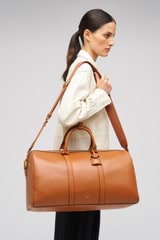 Profile view of model wearing the Oroton Wanderer Weekender in Amber and Smooth leather for Women