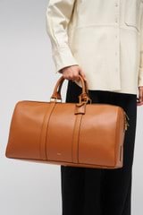 Profile view of model wearing the Oroton Wanderer Weekender in Amber and Smooth leather for Women