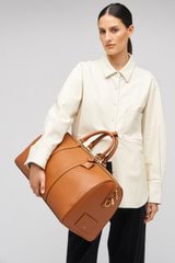 Profile view of model wearing the Oroton Wanderer Weekender in Amber and Smooth leather for Women