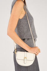 Profile view of model wearing the Oroton Dylan Small Saddle Bag in Cream and  for Women