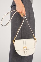 Profile view of model wearing the Oroton Dylan Small Saddle Bag in Cream and  for Women