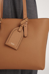 Profile view of model wearing the Oroton Eve Luggage Tag in Tan and Pebble leather for Women