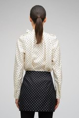 Profile view of model wearing the Oroton Spot Mini Skirt in Black/Cream and 100% Silk for Women