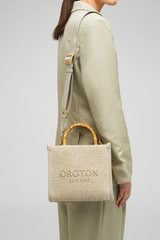 Profile view of model wearing the Oroton Lane Straw Tote in Laurel and Woven Straw With Leather Trim for Women