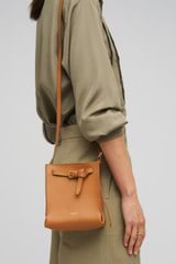 Profile view of model wearing the Oroton Margot Tiny Bucket Bag in Dark Camel and Smooth Leather Lining for Women