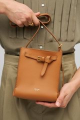 Profile view of model wearing the Oroton Margot Tiny Bucket Bag in Dark Camel and Smooth Leather Lining for Women