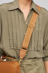 Profile view of model wearing the Oroton Logo Bag Strap in Dark Camel and Smooth Leather And Webbing for Women