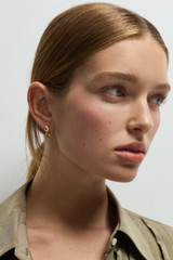 Profile view of model wearing the Oroton Ribbon Twist Huggies in Gold and  for Women