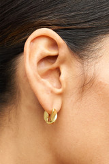 Profile view of model wearing the Oroton Ribbon Twist Huggies in Gold and  for Women