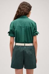 Profile view of model wearing the Oroton Wren Poplin Shirt in Villa Green and Made from 100% poplin cotton  for Women