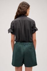 Profile view of model wearing the  Hazel Ruffle Blouse in Washed Black and Made from 100% poplin cotton  for Men