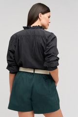 Profile view of model wearing the  Hazel Ruffle Blouse in Washed Black and Made from 100% poplin cotton  for Men