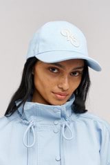 Profile view of model wearing the Oroton Oro Logo Cap in Denim Blue and High-quality 100% cotton   for Women