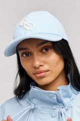 Profile view of model wearing the Oroton Oro Logo Cap in Denim Blue and High-quality 100% cotton   for Women