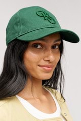 Profile view of model wearing the Oroton Oro Logo Cap in Villa Green and High-quality 100% cotton   for Women