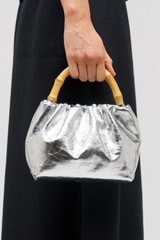 Profile view of model wearing the Oroton Gretel Metallic Mini Top Handle in Silver and Foil texture leather for Women