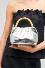 Profile view of model wearing the Oroton Gretel Metallic Mini Top Handle in Silver and Foil texture leather for Women