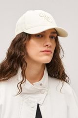 Profile view of model wearing the Oroton Oro Logo Cap in Antique White and High-quality 100% cotton   for Women