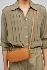 Profile view of model wearing the Oroton Margot Camera Bag in Dark Camel and Pebble Leather exterior for Women