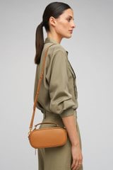 Profile view of model wearing the Oroton Margot Camera Bag in Dark Camel and Pebble Leather exterior for Women