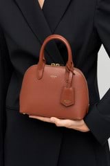 Profile view of model wearing the Oroton Muse Micro Griptop in Barn Red and Two tone saffiano/smooth leather for Women