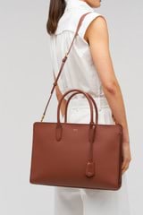 Profile view of model wearing the Oroton Muse 15" Worker Tote in Barn Red and Saffiano leather material for Women