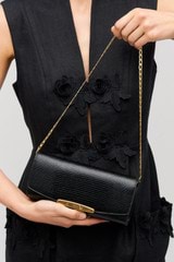 Profile view of model wearing the Oroton Nelle Texture Clutch in Black and Embossed leather material for Women