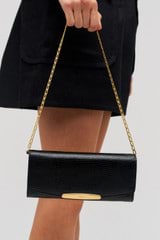 Profile view of model wearing the Oroton Nelle Texture Clutch in Black and Embossed leather material for Women