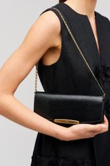 Profile view of model wearing the Oroton Nelle Texture Clutch in Black and Embossed leather material for Women