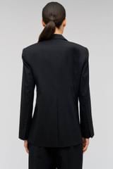 Profile view of model wearing the Oroton Wrap Blazer in Black and 98% wool,  2% elastane material for Women