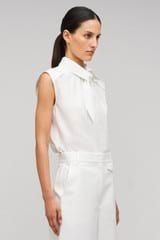 Profile view of model wearing the Oroton Sleeveless Tie Neck Shirt in White and 100% cotton material for Women