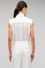 Profile view of model wearing the Oroton Sleeveless Tie Neck Shirt in White and 100% cotton material for Women