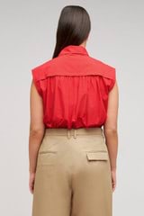 Profile view of model wearing the Oroton Sleeveless Tie Neck Shirt in Poppy and 100% cotton material for Women