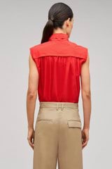 Profile view of model wearing the Oroton Sleeveless Tie Neck Shirt in Poppy and 100% cotton material for Women