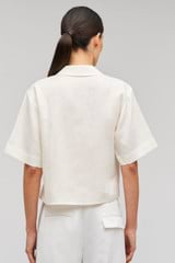 Profile view of model wearing the Oroton Rosebud Lace Camp Shirt in Soft Cream and 100% linen material for Women