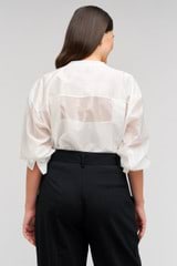 Profile view of model wearing the Oroton Scallop Lace Overshirt in White and 85% Tencel 15% Polyester for Women