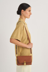 Profile view of model wearing the Oroton Tate Small Day Bag in Brandy and Pebble Leather for Women