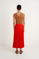 Profile view of model wearing the Oroton Pleat Skirt in True Red and 100% Polyester for Women