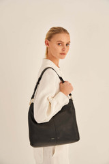 Profile view of model wearing the Oroton Tessa Large Hobo in Black and Soft Pebble Leather for Women