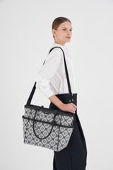 Profile view of model wearing the Oroton Lena Baby Bag, With Mat & Removable Pouch in Black and Oroton Signature Recycled Jacquard Fabric. Smooth Leather for Women