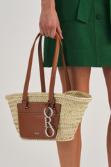 Profile view of model wearing the Oroton Maine Small Tote in Natural/Brandy and Hand Woven Straw With Recycled Leather Trims for Women