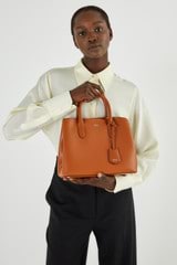 Profile view of model wearing the Oroton Muse Small Three Pocket Day Bag in Cognac and Saffiano And Smooth Leather for 