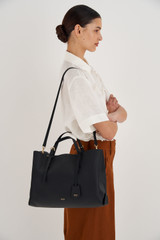 Profile view of model wearing the Oroton Margot Large Day Bag in Black and Pebble Leather for Women