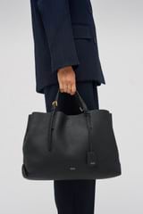 Profile view of model wearing the Oroton Margot Large Day Bag in Black and Pebble Leather for Women
