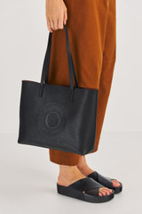 Profile view of model wearing the Oroton Polly Medium Tote in Black and Pebble Leather for Women