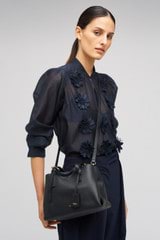 Profile view of model wearing the Oroton Margot Mini Day Bag in Black and Pebble Leather for Women