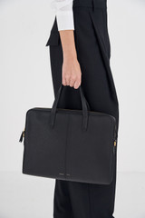 Profile view of model wearing the Oroton Lilly Laptop Bag in Black and Pebble leather for Women