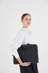 Profile view of model wearing the Oroton Lilly Laptop Bag in Black and Pebble leather for Women